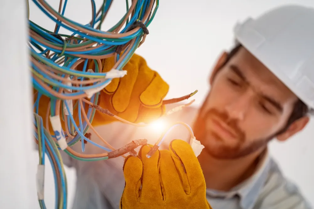 Blogs 2 Licensed electrician in a hard hat and safety gloves working on electrical wiring